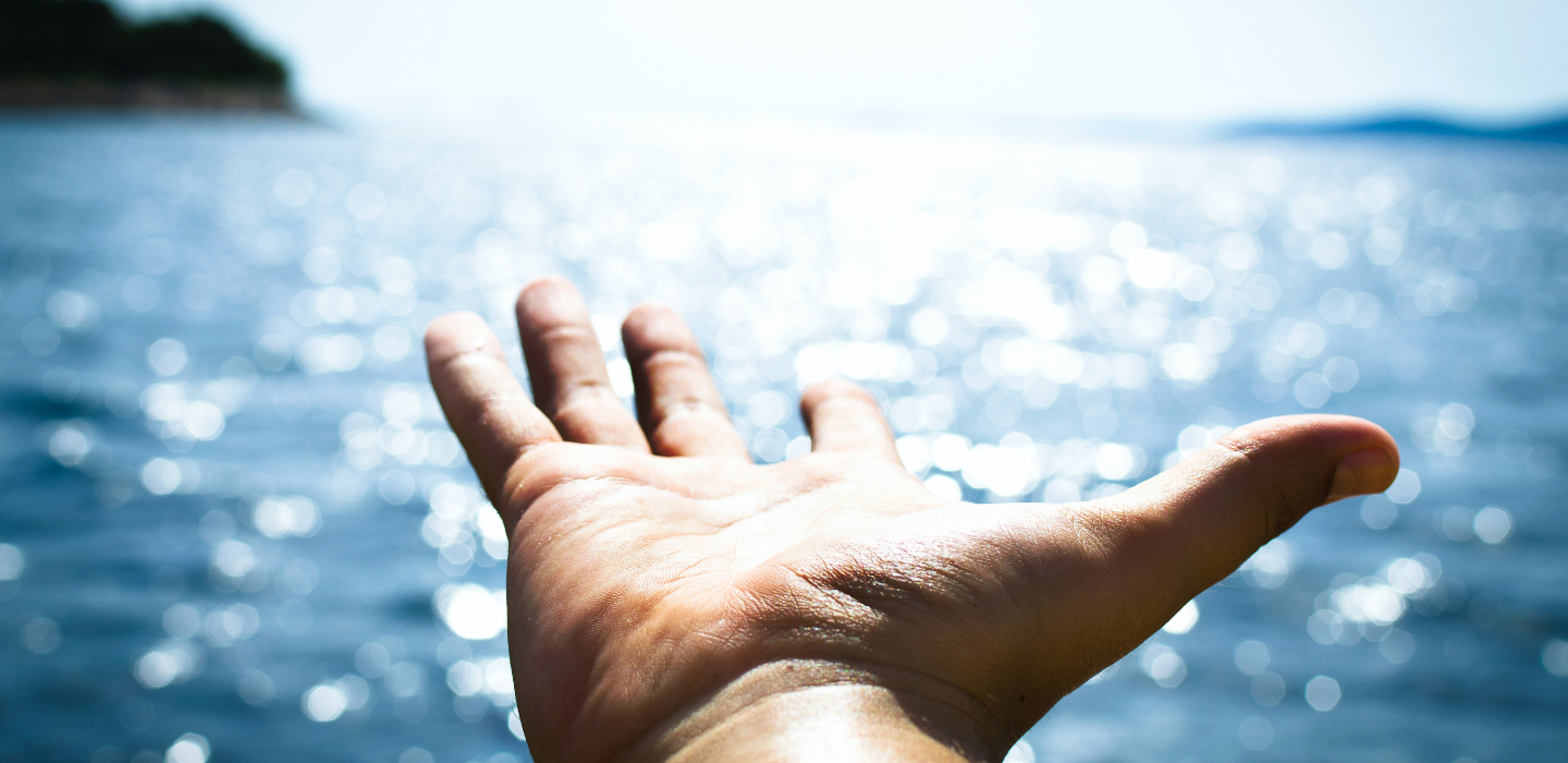 Hand reaching out over the water 